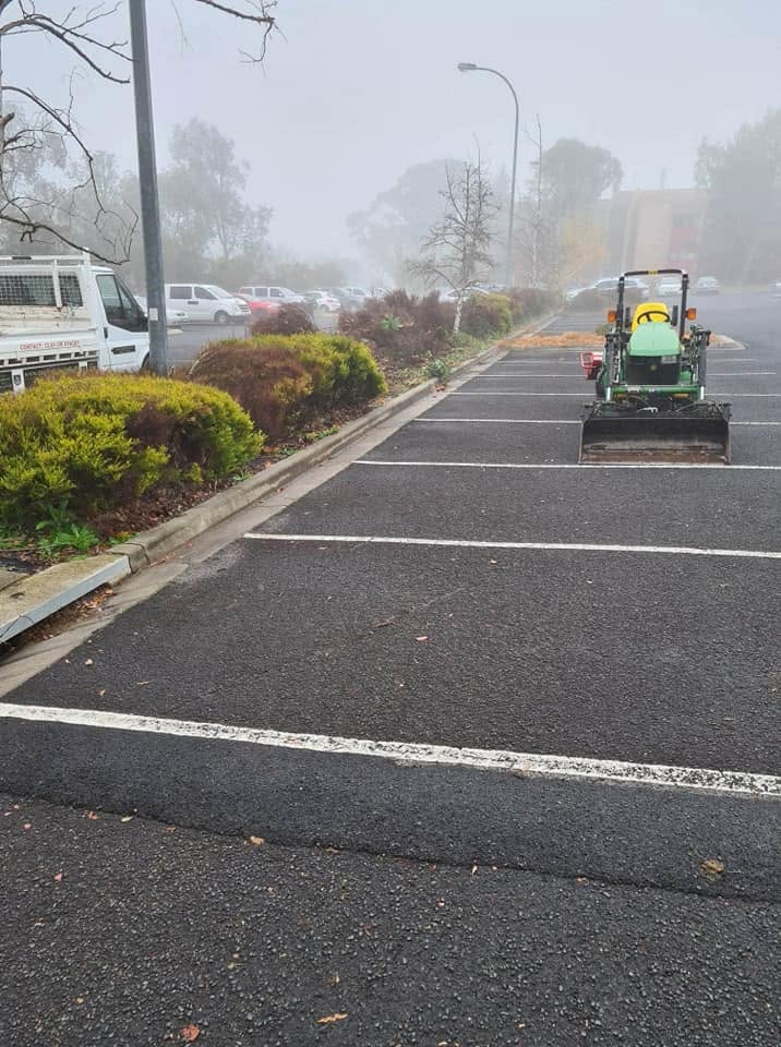 Ride-on mower working a commercial car park garden bed