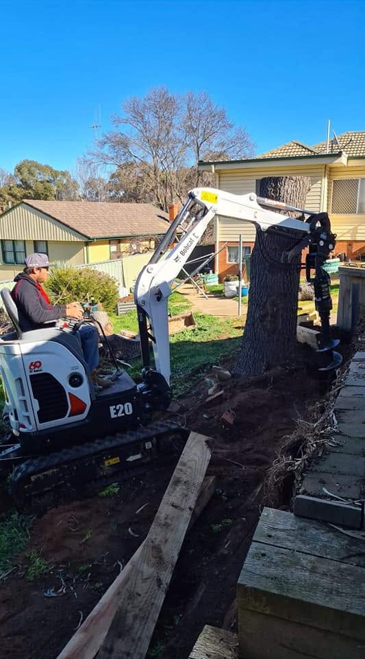Bobcat with auger attachment drilling beside a residential home