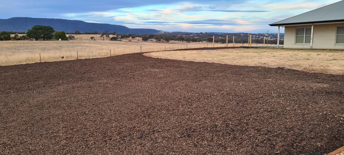 Freshly edged mulch garden bed along a rural property fence line