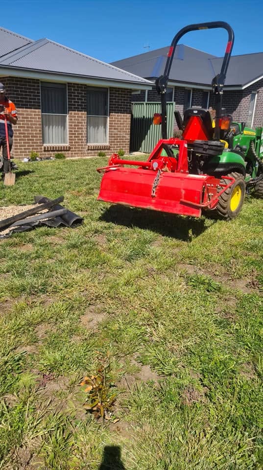 Flail mower attachment clearing overgrown grass and weeds on a residential property